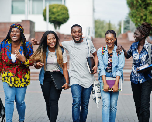 Group of five african college students spending time together on campus at university yard. Black afro friends studying. Education theme.